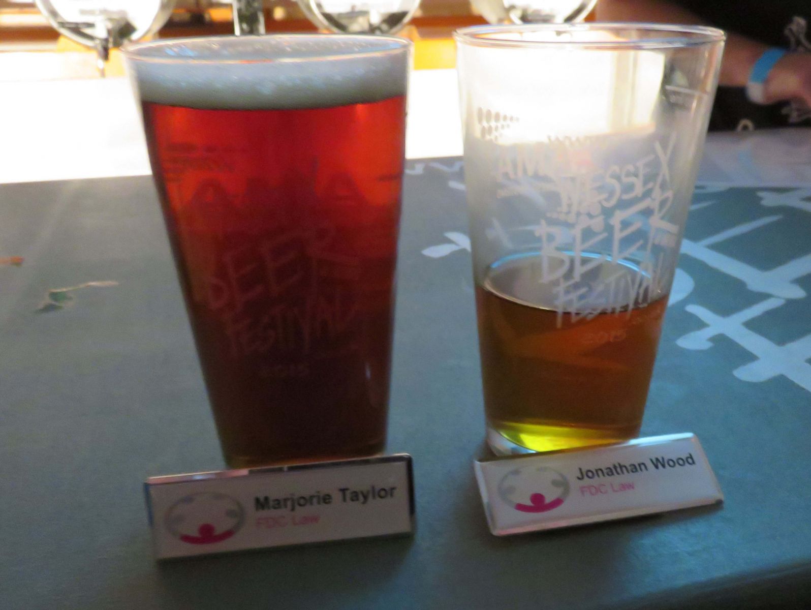 two beer glasses, one full, one half empty, plus 2 name badges