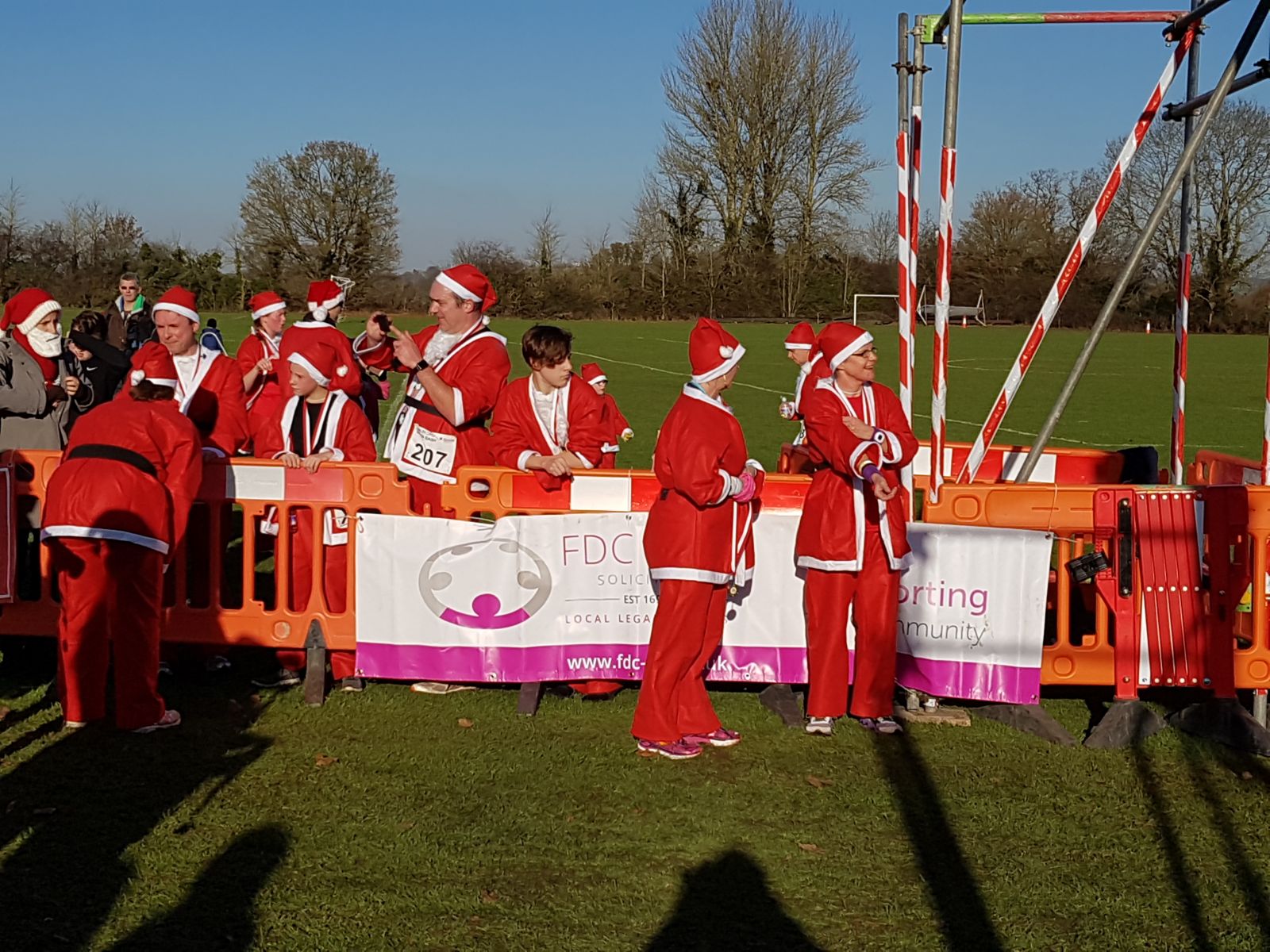 Group of people all dressed as Santa, next to FDC Law banner