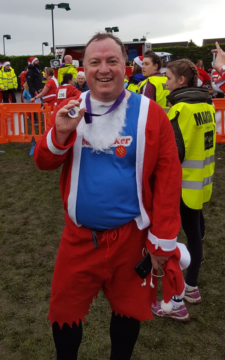 Simon Twose dressed as Santa holding medal